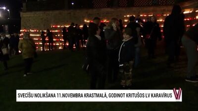Cilvēki noliek svecītes pie Rīgas pils mūra, godinot kritušos karavīrus